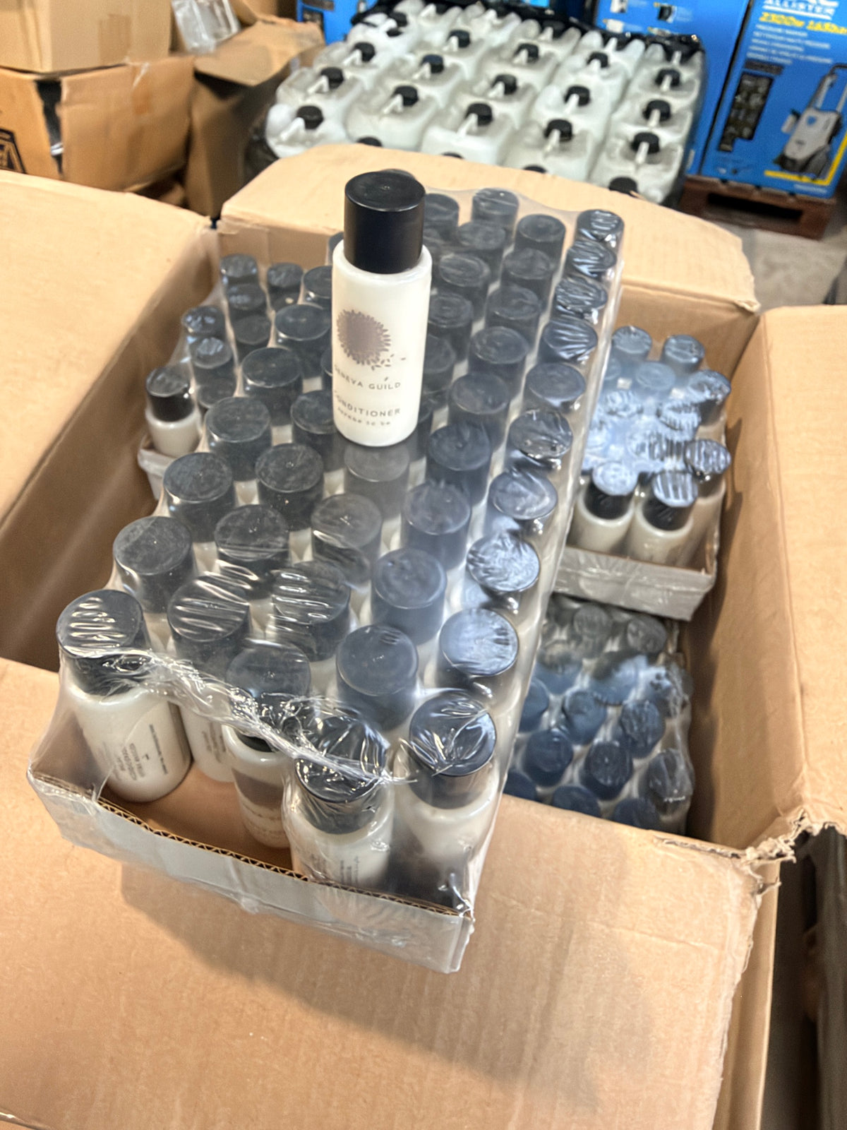 Open box of Geneva Guild 30ml conditioner bottles in shrink-wrapped trays