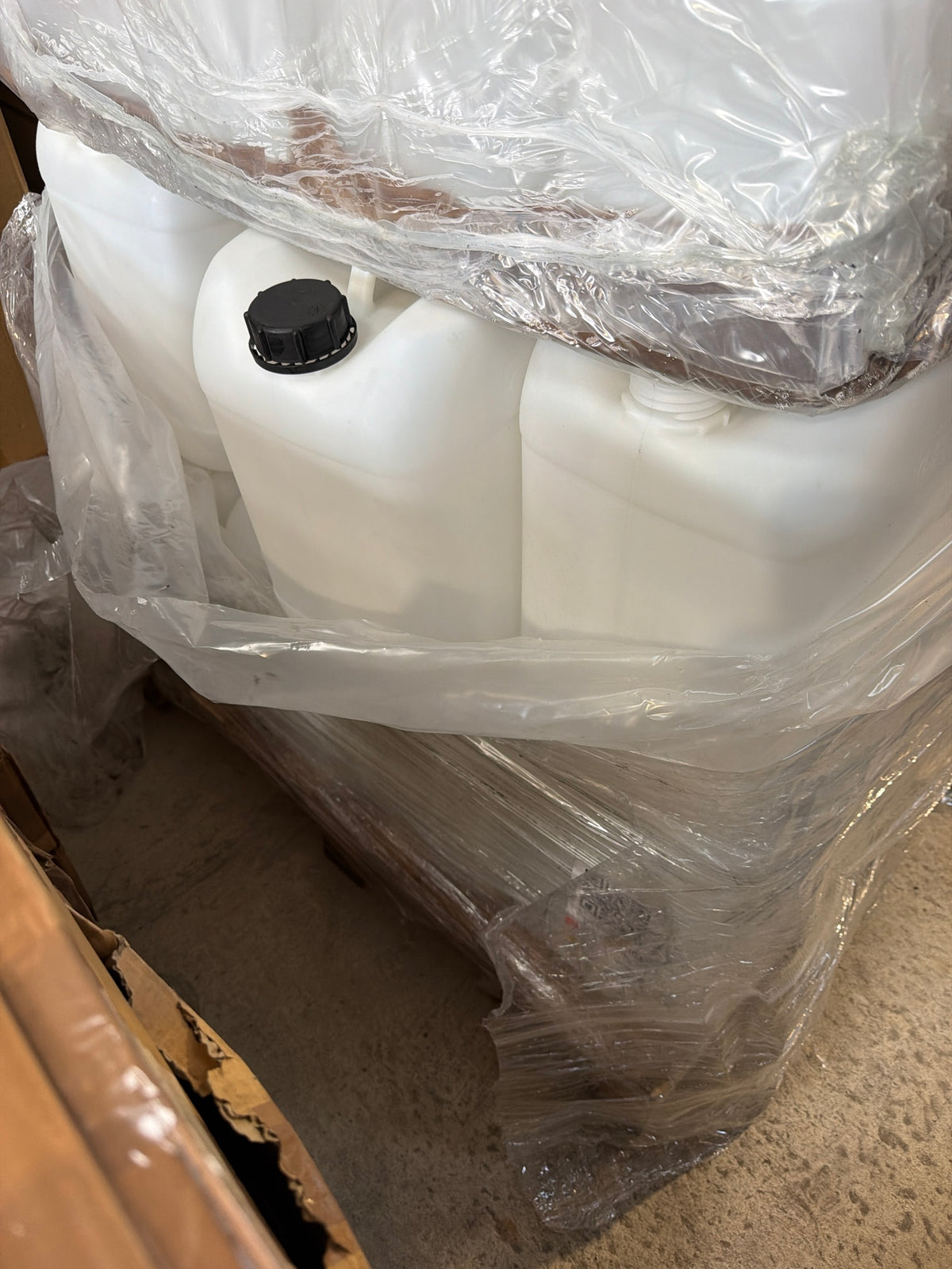 20L natural HDPE jerry cans on pallet, one with black screw cap fitted