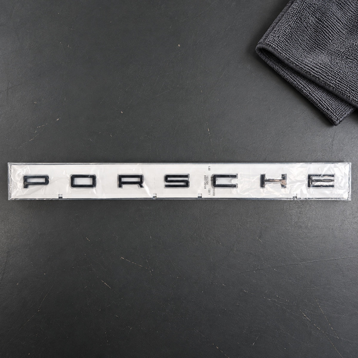 Black aftermarket Porsche seven-letter badge set in packaging