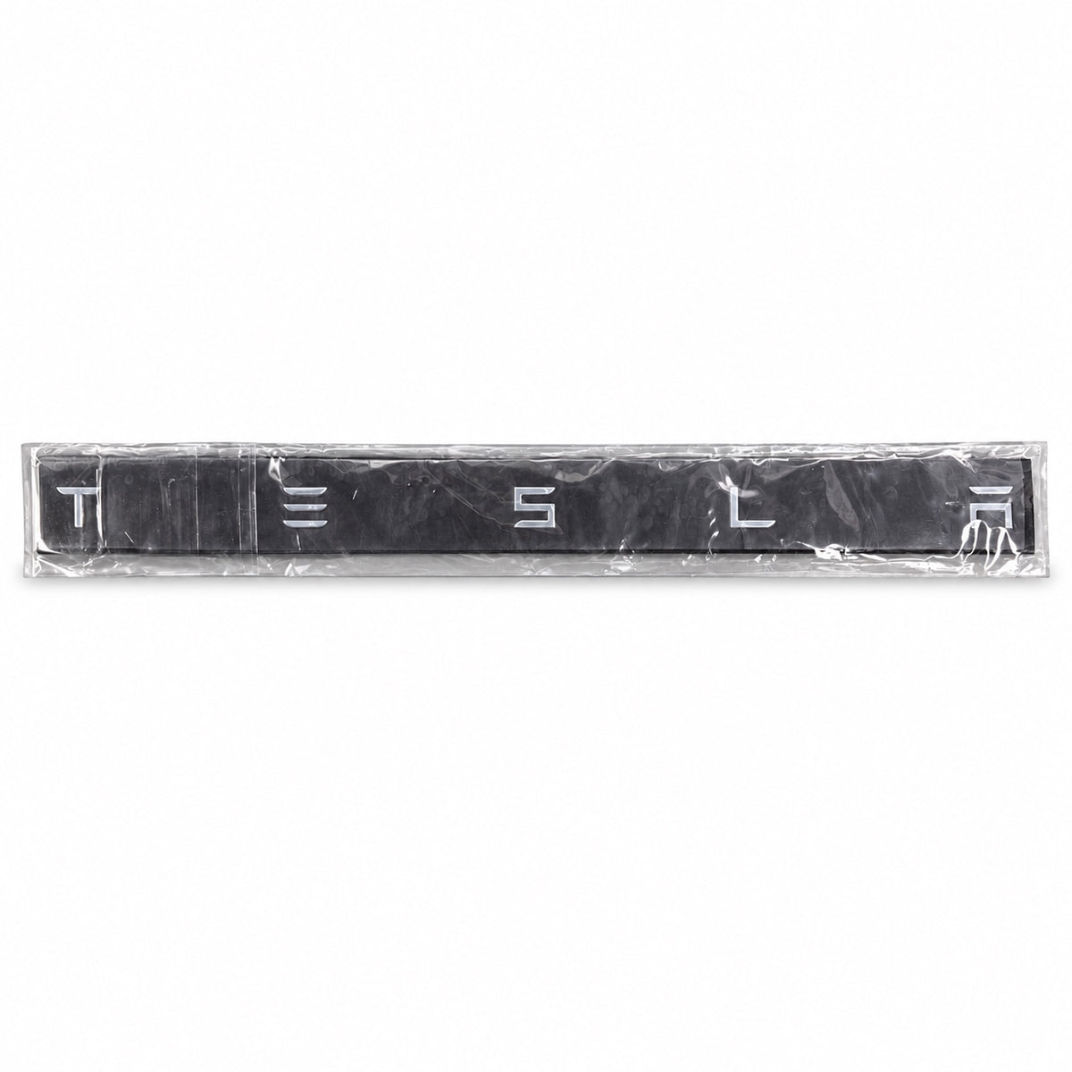 Silver-coloured aftermarket Tesla lettering set in protective packaging