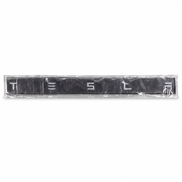 Silver-coloured aftermarket Tesla lettering set in protective packaging