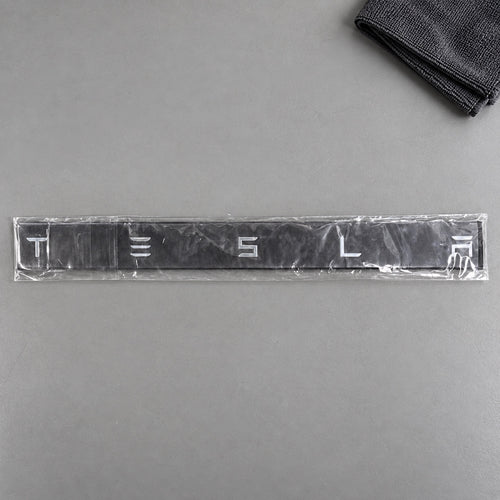 Silver-coloured aftermarket Tesla lettering set in protective packaging