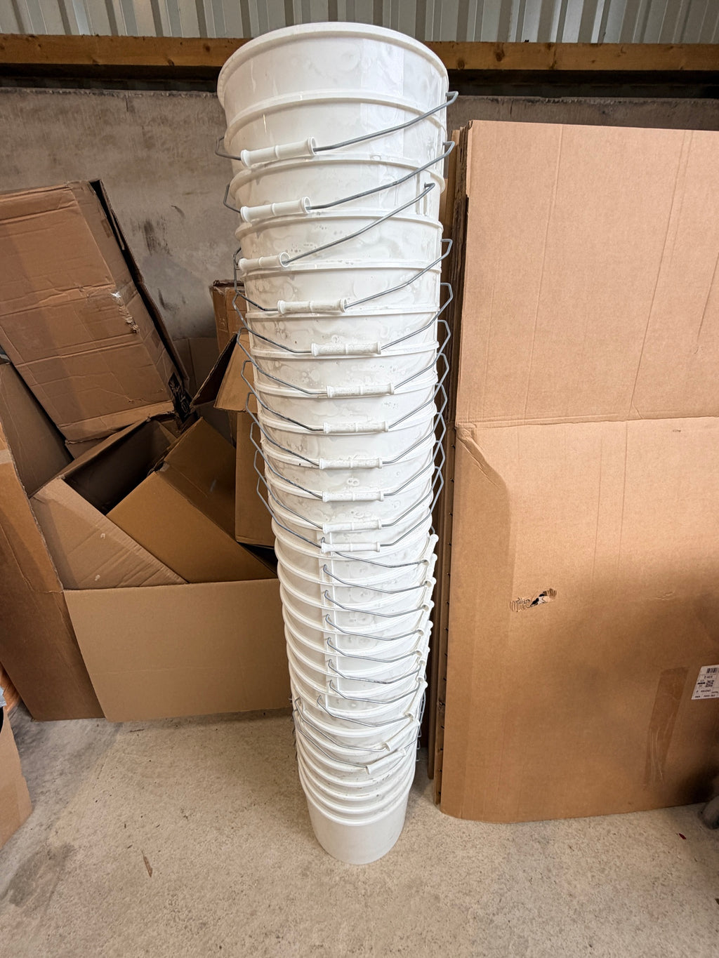 Stack of 27 white plastic buckets with metal handles