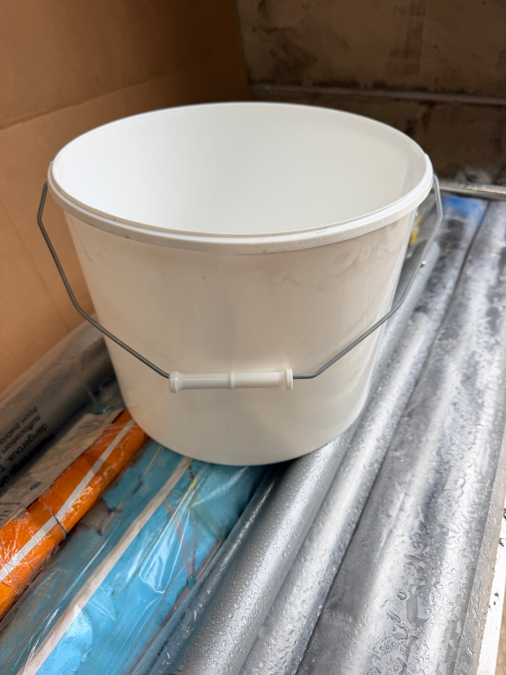 White plastic bucket with steel wire handle and plastic grip
